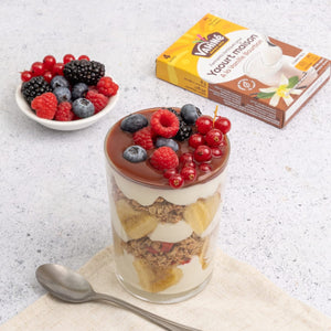 Cette image présente un parfait de dessert en couches avec des baies sur le dessus, à côté d'un bol de fruits rouges mélangés et d'un emballage de produit Dr. Oetker.