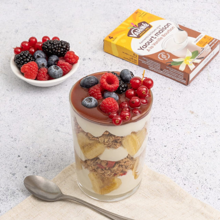 Cette image présente un parfait de dessert en couches avec des baies sur le dessus, à côté d'un bol de fruits rouges mélangés et d'un emballage de produit Dr. Oetker.