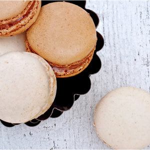 Gros plan sur un assortiment de macarons dans un plat noir décoratif.