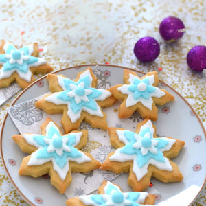 Une assiette de biscuits en forme de flocon de neige dACcorACs de glaA?age bleu et blanc, ACvoquant un thA?me festif de vacances d'hiver.