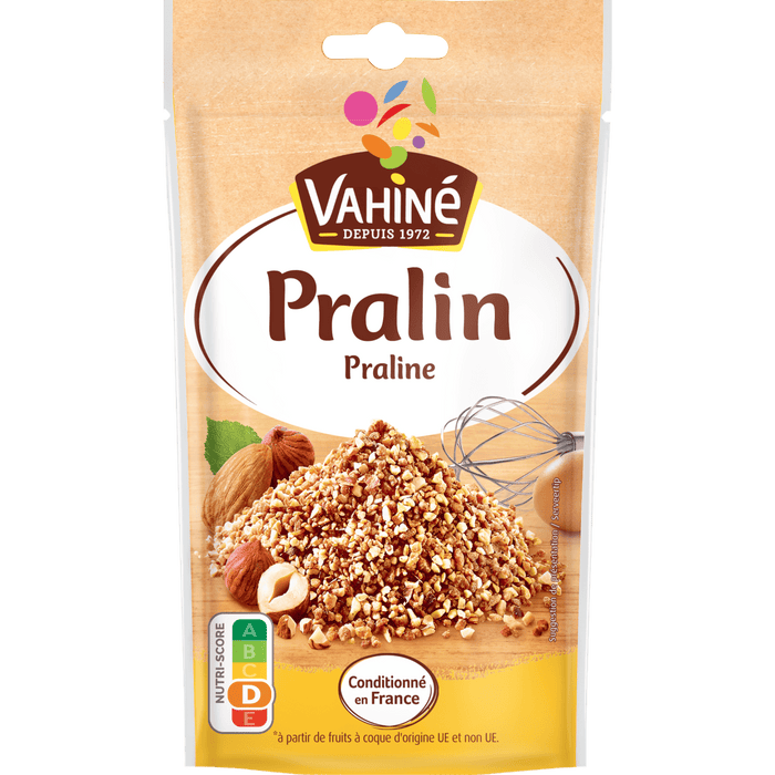 Un paquet de Vahiné Pralin présentant un tas de morceaux de pralin avec des noisettes et des amandes.
