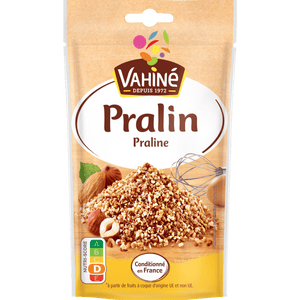 Un paquet de Vahiné Pralin présentant un tas de morceaux de pralin avec des noisettes et des amandes.