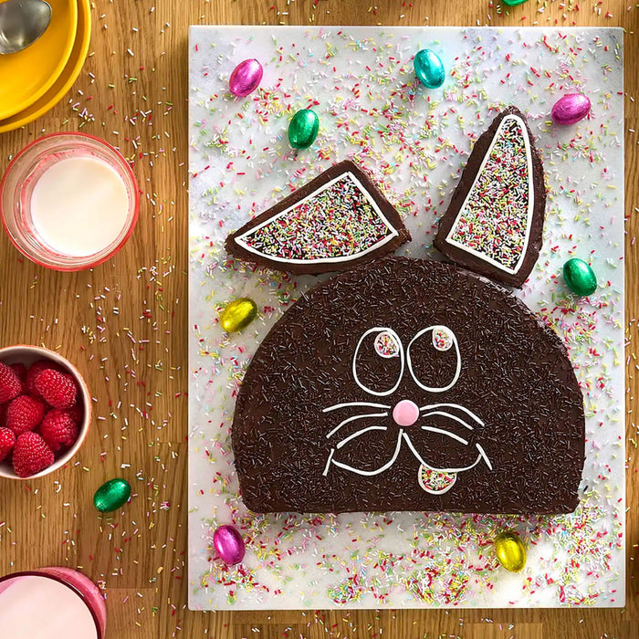 Un gActeau de lapin en chocolat dACcorAC de vermicelles et de glaA?age, entourAC de bonbons colorACs et de framboises fraARches, ACvoque une cAClACbration festive de PAcques.