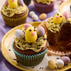 Une assiette de cupcakes de PAcques dACcorACs de glaA?age jaune, de vermicelles au chocolat, d'A?ufs en bonbons et d'un poussin.