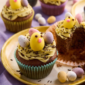 Une assiette de cupcakes de PAcques dACcorACs de glaA?age jaune, de vermicelles au chocolat, d'A?ufs en bonbons et d'un poussin.