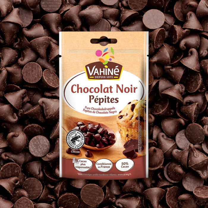 Un sac de pépites de chocolat noir Valhrona est présenté au milieu d'une dispersion des mêmes pépites de chocolat.