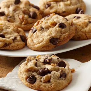Une assiette de biscuits aux pépites de chocolat et aux noix fraîchement sortis du four, parfaits pour une gâterie sucrée.