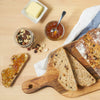 Un pain aux noix et aux fruits est prACsentAC avec du beurre, de la confiture et un pot de noix, suggACrant un dAClicieux petit-dACjeuner ou une collation.