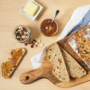 Un pain aux noix et aux fruits est prACsentAC avec du beurre, de la confiture et un pot de noix, suggACrant un dAClicieux petit-dACjeuner ou une collation.