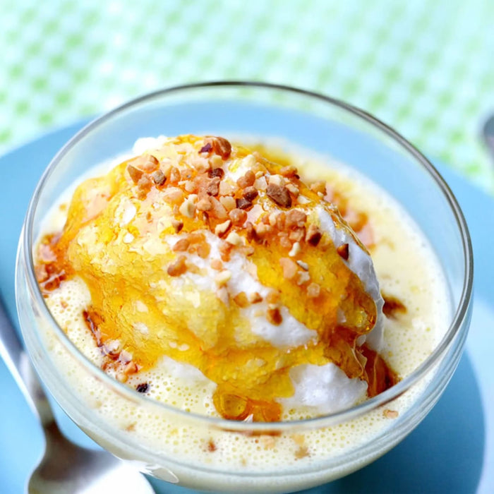 Un gros plan d'A?le flottante, un dessert franA?ais composAC de meringue flottant sur une crA?me anglaise, arrosAC de caramel et parsemAC de noix, servi dans un bol en verre.