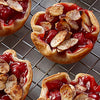 Un gros plan de mini-tartes aux cerises garnies d'amandes grillées sur une grille, présentant une délicieuse option de dessert.