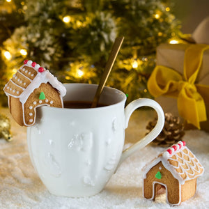 Une scA?ne festive mettant en scA?ne une tasse de thAC ornACe de maisons en pain d'ACpices, ACvoquant une atmosphA?re de NoA<l chaleureuse.