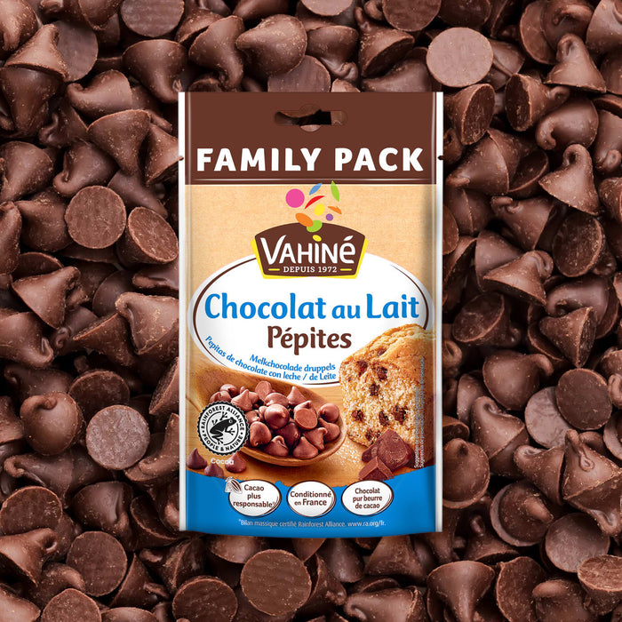 Un paquet familial de pépites de chocolat au lait Vahiné est présenté sur un fond de pépites de chocolat éparpillées.