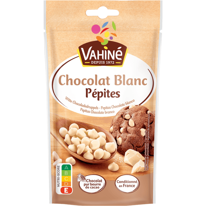 Un paquet de pépites de chocolat blanc Vahiné, une marque McCormick, est présenté à côté d'un biscuit aux pépites de chocolat.