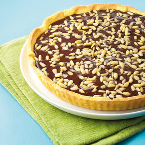 Une dAClicieuse tarte au chocolat garnie de graines de tournesol est posACe sur une assiette avec une serviette verte.