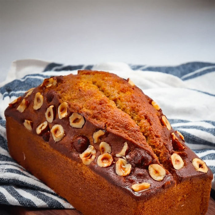 Un pain de gâteau aux noisettes posé sur un tissu rayé.