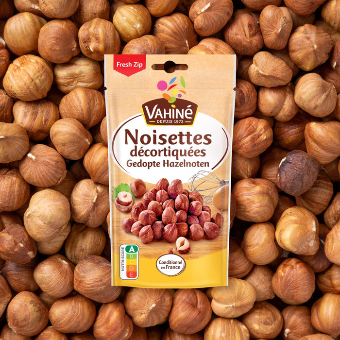 Un sachet de Noisettes décortiquées Vahine est présenté sur un fond de noisettes en vrac.