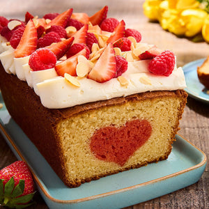 Un cake en forme de pain avec un cA?ur au centre, garni de glaA?age et de fraises et framboises fraARches.
