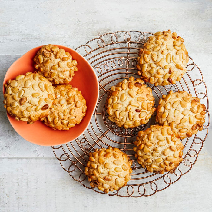 Une assiette et une grille de refroidissement présentent plusieurs biscuits aux pignons dorés, mettant en valeur leur surface texturée et leur aspect invitant.