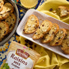 Une assiette de biscotti avec des Vahiné Raisins secs est présentée sur un tissu jaune, à côté d'un sachet de raisins.