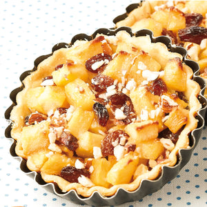 Gros plan d'une petite tarte aux pommes avec des raisins secs et une croûte feuilletée.