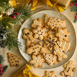 Un arrangement festif de biscuits au pain d'ACpices de diffACrentes formes, comme des flocons de neige, des bonhommes en pain d'ACpices et des sapins de NoA<l, dACcorACs de glaA?age blanc, entourACs de dACcorations de NoA<l.