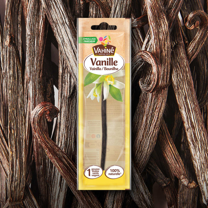 Une gousse de vanille Anisette Vanille emballACe individuellement est prACsentACe sur un fond de gousses de vanille en vrac.