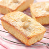 Un gros plan de blondies rectangulaires garnis de noix de macadamia et de sucre glace, prACsentACs sur une grille.