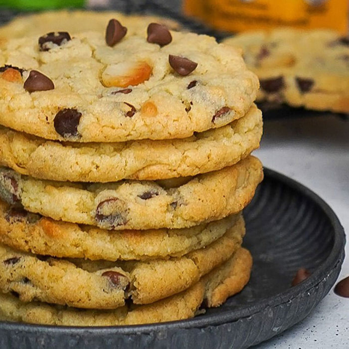 Une pile de biscuits aux pACpites de chocolat fraARchement sortis du four sur une assiette foncACe met en valeur leur couleur dorACe et leur texture allACchante.