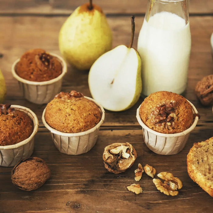 Un arrangement rustique de muffins aux poires, de poires fraARches, de noix et d'une bouteille de lait sur une surface en bois suggA?re un petit-dACjeuner ou une collation faits maison.