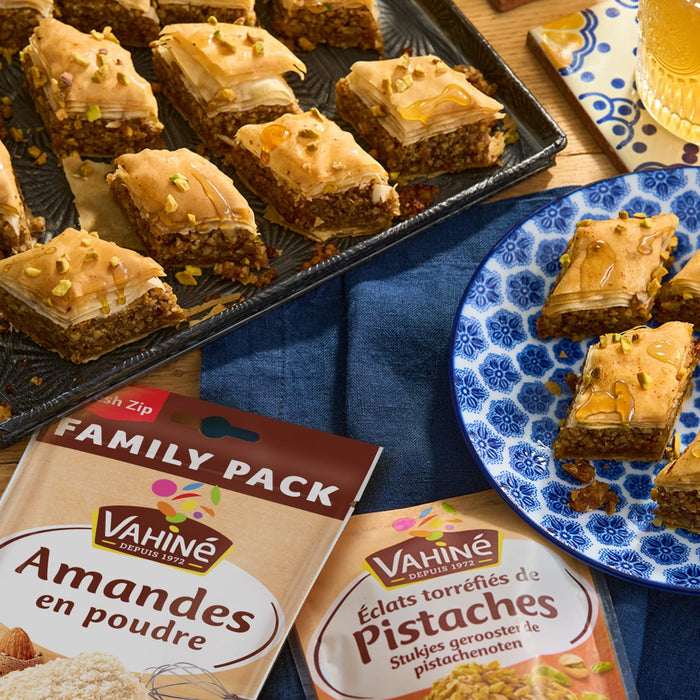 Un plateau et une assiette de baklava sont prACsentACs avec des paquets de poudre d'amandes et de pistaches VahinAC Family Pack.