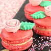 Gros plan de macarons rouges dACcorACs de roses et de feuilles, prACsentant un dessert dAClicat et AClACgant.