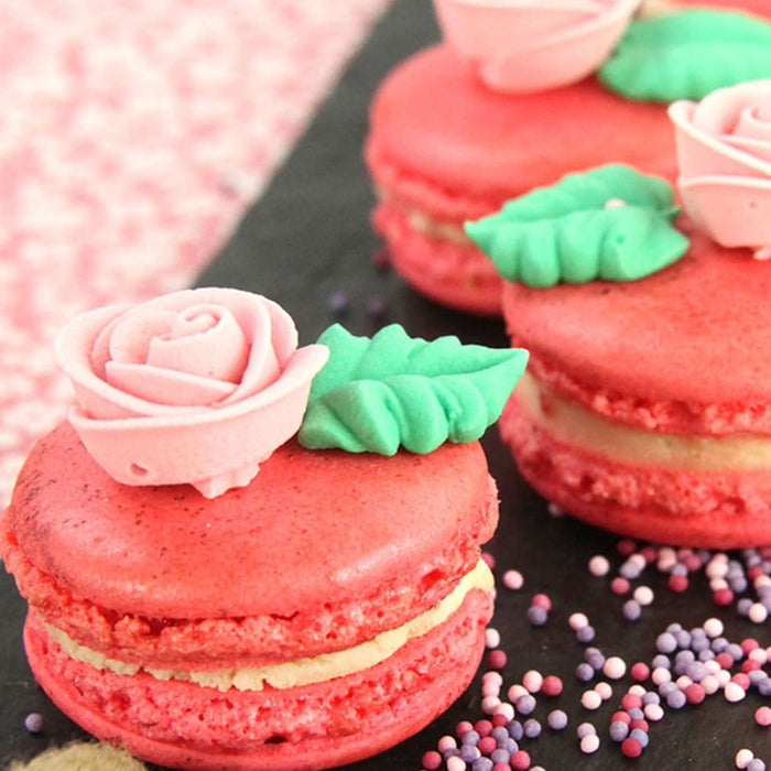 Gros plan de macarons rouges dACcorACs de roses et de feuilles, prACsentant un dessert dAClicat et AClACgant.