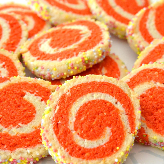 Une pile de biscuits spirales colorACs avec des tourbillons rouges et des vermicelles arc-en-ciel.