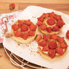 Trois tartelettes aux fraises sont disposACes sur une assiette blanche, prACsentant une dAClicieuse option de dessert.