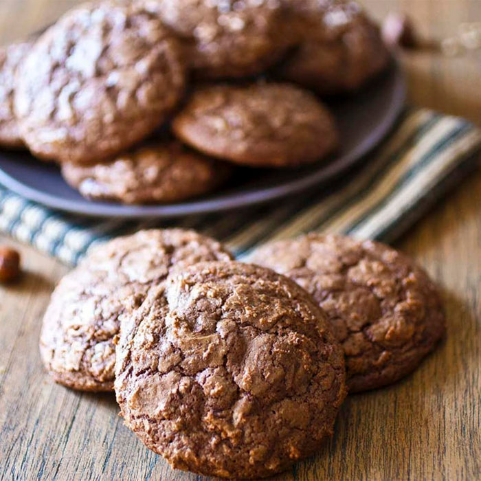 Un arrangement tentant de biscuits au chocolat et aux noisettes présentés sur une surface en bois et une assiette grise.