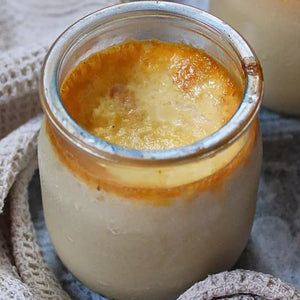 Un dessert crACmeux, possiblement une crA?me brA>lACe ou une crA?me anglaise, est servi dans un petit pot en verre avec un dessus caramAClisAC.