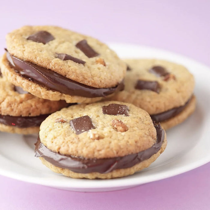 Une pile de sandwichs aux biscuits aux pépites de chocolat avec une garniture crémeuse au chocolat.
