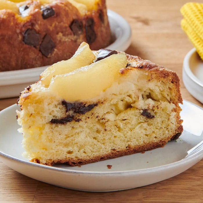 Une part de gActeau aux poires et au chocolat est prACsentACe sur une assiette, mettant en valeur sa texture moelleuse et ses dAClicieuses garnitures.