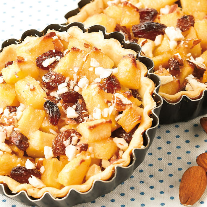 Deux tartelettes aux pommes avec des raisins secs et des amandes sont prACsentACes, mettant en valeur une dAClicieuse option de dessert.