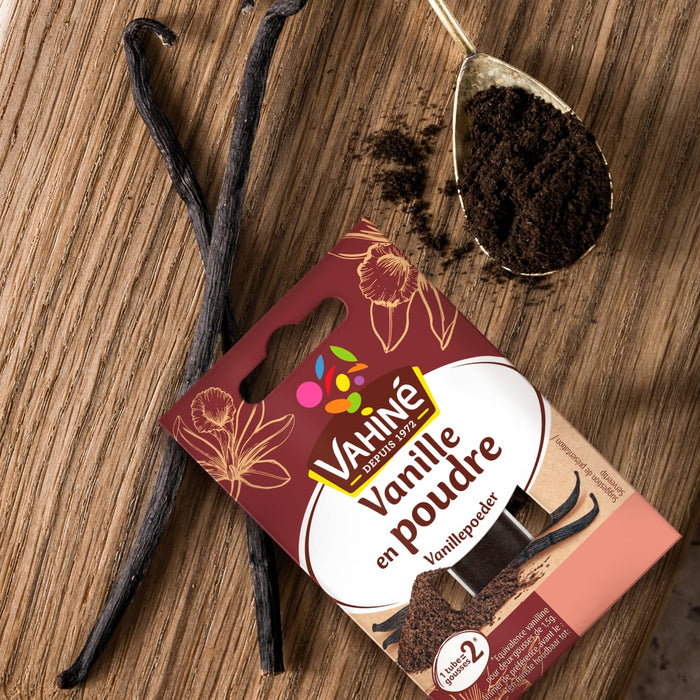 Un paquet de VahinAC Vanille en poudre est prACsentAC avec des gousses de vanille et de la poudre de vanille sur une surface en bois.