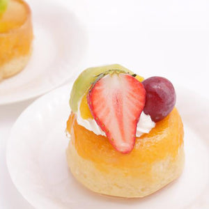 Une petite pâtisserie garnie de fruits est posée sur une assiette blanche, présentant une option de dessert colorée et attrayante.