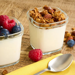 Deux petits rACcipients en verre remplis de yaourt, l'un garni de baies et l'autre de granola, suggACrant une option de petit-dACjeuner ou de collation saine.