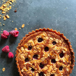 Une tarte aux amandes et aux fruits rouges d'aspect dAClicieux avec des amandes grillACes sur un fond sombre, suggACrant un dessert fait maison.