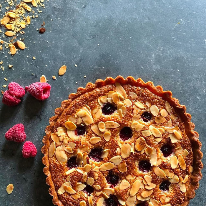 Une tarte aux amandes et aux fruits rouges d'aspect dAClicieux avec des amandes grillACes sur un fond sombre, suggACrant un dessert fait maison.