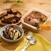 Un dessert dAClicieux composAC de crA?me glacACe au chocolat, de morceaux de brownie et de sirop de chocolat, prACsentAC dans un bol et un rACcipient A? cA?tAC de brownies supplACmentaires.