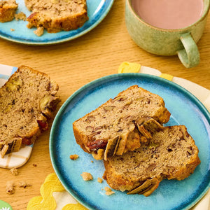 Une tranche de pain aux bananes est prACsentACe sur une assiette bleue A? cA?tAC d'une tasse, suggACrant un petit-dACjeuner ou une collation agrACable.
