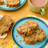 Une tranche de pain aux bananes est prACsentACe sur une assiette bleue A? cA?tAC d'une tasse, suggACrant un petit-dACjeuner ou une collation agrACable.