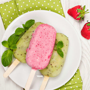 Une assiette de rafraARchissants popsicles aux fruits faits maison, incluant des saveurs de fraise et de kiwi, garnis de menthe fraARche et de fraises.