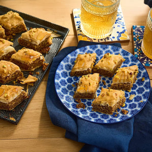 Une assiette de baklava est posACe A? cA?tAC d'un plateau contenant davantage de baklava et de deux verres de thAC glacAC, suggACrant qu'une douceur est apprACciACe.